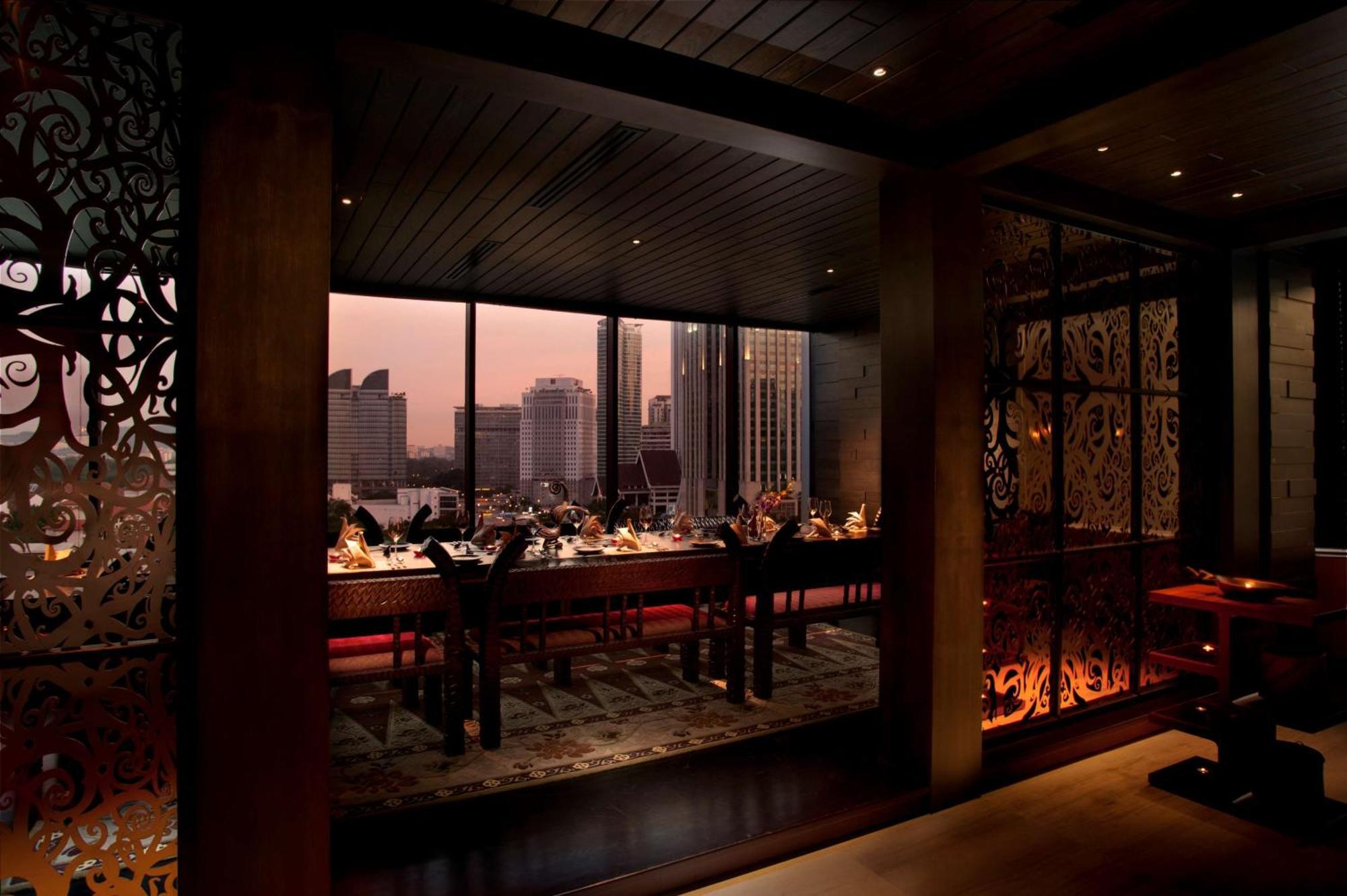 Doubletree By Hilton Kuala Lumpur Hotel Екстериор снимка The photo depicts a modern dining area in a restaurant, featuring a long table set for a meal. The room has a warm, inviting atmosphere, illuminated by soft lighting. Large windows provide a view of the city skyline, possibly during sunset, creating 