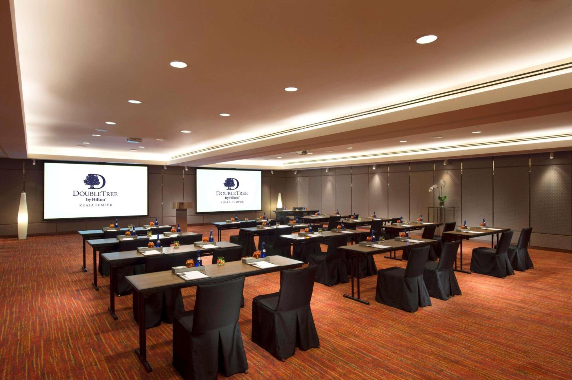 Doubletree By Hilton Kuala Lumpur Hotel Екстериор снимка The image shows a conference or meeting room setup. There are several rows of tables arranged for participants, each covered with a black tablecloth. The tables are equipped with stationery, suggesting that the space is intended for a professional ga